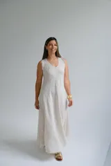 Vestido largo color beige confeccionado en lino italiano, de corte recto, sin mangas y escote en V. Presenta ruedo desflecado.