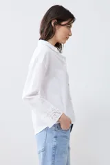Camisa blanca de manga larga con cuello y puños bordados con calados. Corte clásico y cierre frontal con botones.