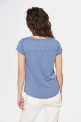 Remera color beige con escote redondo, manga corta, bolsillo en el pecho y cierre parcial con botones.