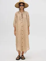 Vestido midi color beige con estampado de círculos y cuello mao, con mangas 3/4 abullonadas y cierre frontal con botones. Incluye cinturón de cuero marrón.