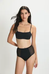 Conjunto de bikini negro con top de breteles finos y bombacha tiro alto con paneles de tul transparente en los laterales.