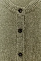 Chaqueta de punto color rosa pálido, con cuello redondo y cierre frontal de botones oscuros. Presenta mangas largas y un corte a la cintura.