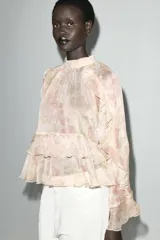 Camisa de cuello subido y manga larga con estampado floral en tonos rosa y verde. Detalle de volantes en cuello, mangas y ruedo. Cierre en espalda con abertura y botones.