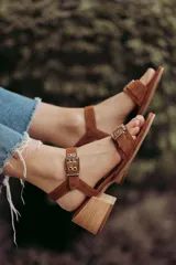 Sandalia de gamuza color marrón claro con correa ancha y doble hebilla metálica plateada, diseñada para ofrecer comodidad y estilo.