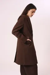 Blazer largo marrón con solapas de muesca, cierre frontal con dos botones y bolsillos laterales con solapa.