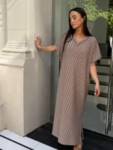 Vestido largo de tejido a rayas horizontales en tonos beige y blanco, con escote en V y mangas cortas tipo murciélago. Presenta tajos laterales en el ruedo.