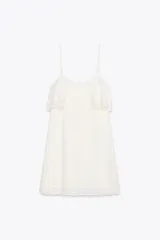 Vestido corto blanco con tirantes finos ajustables, escote recto, detalle de bordados y volantes, tejido elástico tipo nido de abeja y forro interior combinado a tono.