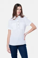 Camisa blanca de lino y algodón, con cuello clásico, mangas cortas y cierre frontal parcial con botones.
