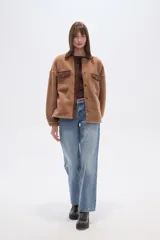 Campera estilo camisa (shacket) de tejido tipo borrego o sherpa color crema, con cuello y tapeta de pana marrón. Posee dos bolsillos frontales con tapa y botones a presión.