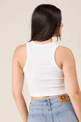 Top tipo musculosa de punto acanalado en color blanco, con cuello redondo y cierre de cremallera frontal.