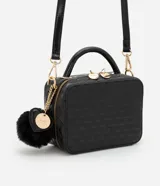 Cartera camera bag negra, confeccionada en PU con textura geométrica. Tiene asa transversal desmontable, cierre por cremallera y pompón de llavero.