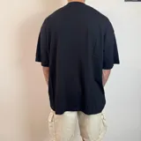 Remera negra de corte oversize con cuello redondo y estampado de sol amarillo en el pecho.