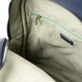 Mochila azul de cuero sintético con diseño tejido. Tiene un compartimento principal con cierre de solapa, un bolsillo interno con cierre y otro abierto. La correa es regulable y los herrajes son plateados.