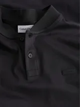 Chomba negra de algodón con cuello mao, manga corta, cartera con dos botones y parche con micro logo en la parte delantera.