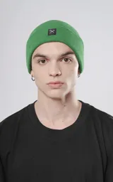 Gorro de lana verde con logo bordado en un parche negro.