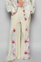 Pantalón de corte flare color crema, con paneles estampados florales y detalles de patchwork a los laterales.