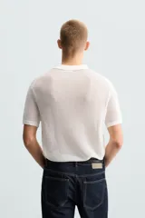 Polo blanco de punto tejido con estructura calada, corte regular fit, cuello solapa con abertura frontal y manga corta.