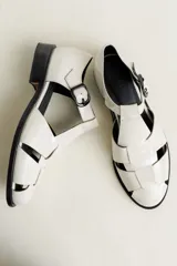 Sandalia roja de cuero vacuno con diseño de tiras entrecruzadas y hebilla lateral. Tiene suela de cuero artesanal y taco bajo.