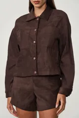 Camisa marrón de gamuza sintética, con cuello clásico, cierre frontal con botones a presión, mangas largas y dos bolsillos de parche en el pecho.