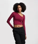 Blusa corta color borgoña, de mangas largas y escote asimétrico.