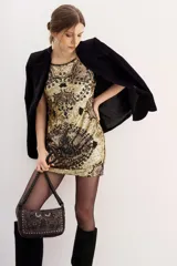 Vestido corto sin mangas, ajustado al cuerpo, con cuello redondo. Confeccionado en tela dorada con bordados y lentejuelas en tonos tierra y negro, formando un diseño ornamental.