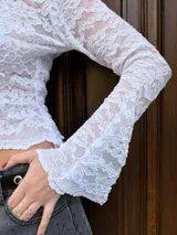 Remera blanca de encaje con mangas largas acampanadas y escote en V.