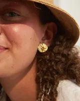 Aros tipo botón dorados con textura irregular que simula la superficie de un molusco.