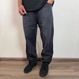 Jean de hombre color negro con efecto lavado, de corte mom fit, con cintura elástica y puños ajustados en los tobillos.