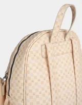 Mochila color crema con estampado geométrico de cuadros, confeccionada en cuerina. Tiene asa corta de mano, correas regulables, doble bolsillo frontal con cierre (uno con dije de corazón) y pouch lateral extraíble con cierre y dije de corazón.