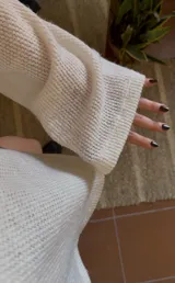 Blusa de tejido de punto color blanco, con escote barco que permite usarla caída sobre un hombro.