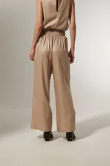 Pantalón ancho de tiro alto color beige metalizado, confeccionado en lino y viscosa, con lazo para ajustar en la cintura.