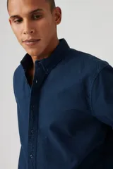 Camisa de manga larga color azul marino, con cuello abotonado (button-down) y corte recto.