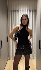Minifalda negra de cuerina con cinturón con hebillas metálicas.