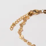 Pulsera dorada con eslabones de cadena y apliques circulares.