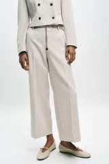 Pantalón tobillero negro de tiro alto con cinturón de cadena dorada. Presenta falsos bolsillos con solapa en la espalda, pernera recta y cierre lateral con cremallera oculta.