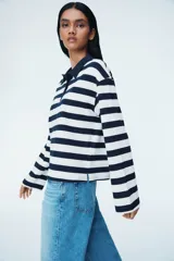 Remera polo de manga larga con cuello clásico y tapeta de botones. Diseño a rayas horizontales blancas y azul marino.