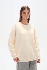 Sweater color crema, de corte holgado, con cuello redondo y mostacillas decorativas.