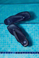 Ojotas de denim (mezclilla) color azul oscuro con tiras anchas acolchadas y un detalle bordado de la letra "N" en cuero en la tira.