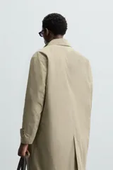 Gabardina color beige de corte recto, con cuello solapa, cierre frontal con botones, bolsillos laterales y puños ajustables con trabilla.