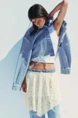 Falda corta de encaje color crema con forro interior. Presenta cintura elástica y bajo asimétrico con terminación en picos.