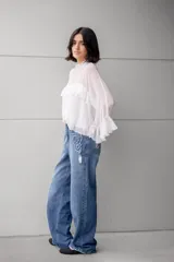 Blusa blanca de gasa con volados en el frente y mangas acampanadas.