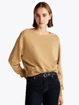 Buzo color beige de felpa de algodón con cuello barco y botones dorados en los hombros.