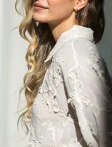 Camisa de algodón color crema, marca Liv Los Angeles, con bordado floral y terminaciones en crochet en puños y ruedo. Tiene cuello con solapa y abertura central con botones.