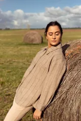 Campera de corte recto con estampado a cuadros en tonos beige y marrón. Tiene cuello camisero, cierre frontal con botones y bolsillos de parche en el pecho.