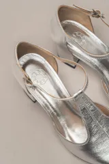 Zapato de vestir negro de cuero, con punta fina, tira en forma de T y hebilla lateral.
