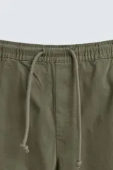 Pantalón cargo negro de corte slim fit, confeccionado en tejido de algodón con cintura elástica ajustable con cordón. Cuenta con bolsillos frontales, traseros y bolsillos tipo parche con solapa en los laterales.
