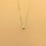 Gargantilla dorada con cadena fina y dije circular con circonia engarzada.