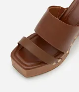 Sandalias de plataforma color marrón con tiras de cuero sintético y tachuelas doradas.