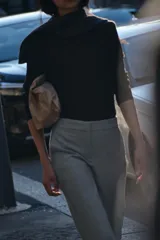 Pantalón gris de vestir, de corte tobillero, con tiro medio, cintura elástica en la parte trasera, bolsillos delanteros y falsos bolsillos traseros.