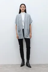 Ruana de tejido de punto color rosa melange, sin mangas y con cuello redondo.